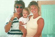 a man, woman and child posing for a photo in front of a mirror with their arms around each other