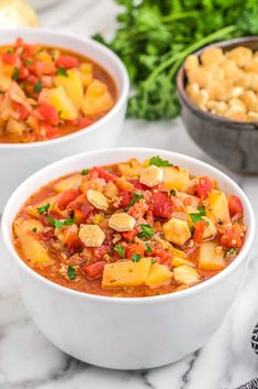 two white bowls filled with vegetable stew and garnished with parsley on the side