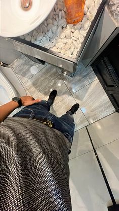 a person laying on the ground in front of a toilet with rocks and pebbles around it