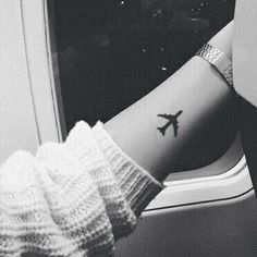 a person's arm with a small airplane tattoo on the left side of their arm