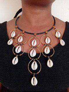 A Set of  African Cowrie Jewelry, Handmade Necklace, Seashell Jewelry, Boho Necklace, One size fits all, Pendant Necklace, EarringsThis set of jewelry is made of brass and cowrie seashell. It will make you stand out in any occasion.Necklace can fit any neck size..This can be a perfect gift for your loved ones. The price is inclusive of one necklace and a pair of matching earrings.We offer wholesale at a fair price,please contact me.***Free shipping on additional items in your cart.*** ***For mor African Cowrie Shell Jewelry, Shell Jewelry For Jewelry Making, Cowrie Shell Dangle Jewelry For Gifts, Cowrie Shell Dangle Jewelry Gift, Bohemian Shell Jewelry With Round Beads, Gold Beaded Shell-shaped Jewelry, Unique Handmade Shell-shaped Necklace, Traditional Adjustable Shell Jewelry, Gold Beaded Shell Jewelry