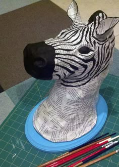 a zebra head on top of a table next to pencils