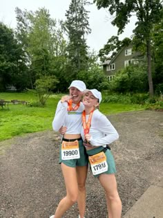 two women are hugging each other in the middle of a race track with trees and grass behind them