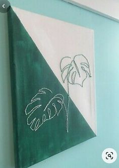 a green and white painting hanging on the side of a blue wall next to a window