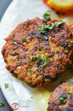 two crab cakes on a plate with lemons and parsley