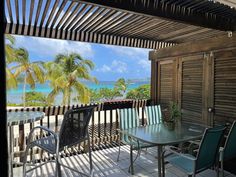 an outdoor patio with table and chairs overlooking the ocean