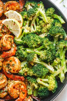 shrimp and broccoli in a skillet with lemon wedges on the side