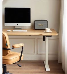 an office desk with a computer, speakers and a cup on the chair next to it