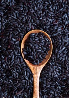 a wooden spoon filled with black rice