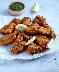 chicken wings with lemon wedges and green sauce