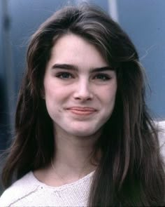 a woman with long brown hair smiling at the camera