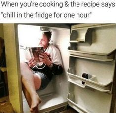 a man sitting in an open refrigerator reading a book