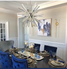 a dining room table with blue chairs and a chandelier hanging from the ceiling