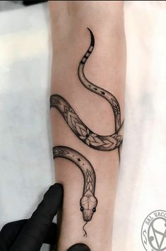 a person with a tattoo on their arm holding onto a snake's head and tail