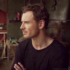 a man with his arms crossed looking off to the side in an old workshop area