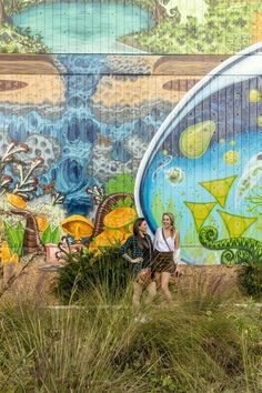 two women are standing in front of a mural