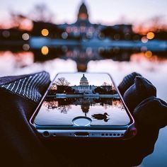 someone holding up their cell phone with the capitol building in the background