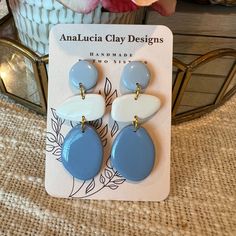 a pair of blue and white earrings sitting on top of a table next to flowers