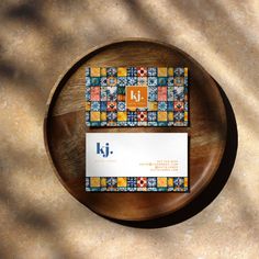 a business card sitting on top of a wooden table next to a plate with an orange and blue pattern