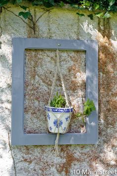 a potted plant is hanging on the side of a stone wall with a blue frame