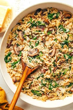 pasta with mushrooms and spinach in a white bowl next to bread on the side