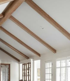 a living room filled with furniture and lots of wood beams on the ceiling, along with large windows