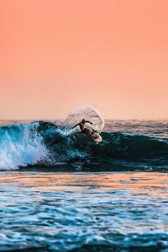 a man riding a wave on top of a surfboard in the middle of the ocean