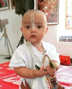 a young child with plastic on his head holding an object in one hand and looking at the camera