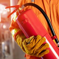 a person in an orange uniform is holding a red fire extinguisher case