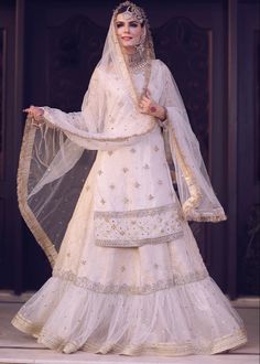 a woman in a white bridal gown with veil and headpiece standing on a stage