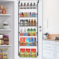 an open pantry door with spice and spices on the shelves next to it, in a white kitchen