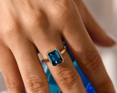 Discover our gorgeous London Blue Topaz ring! It's a deep blue, natural gemstone with stunning color and clarity. The emerald cut weighs about 3.5 Ct. The ring features a unique semi-hidden halo, with options for Diamond or Moissanite. Perfect as a December birthstone gift, or a dazzling proposal or engagement ring. It's also a great anniversary present. Explore our fine jewelry collection today. Enjoy its beauty, charm, and elegance - it's designed just for you!  ★ ★  CUSTOM/DUTY-FREE SHIPPING Vintage Promise Ring, One Year Anniversary Gift, Birthstone Engagement Rings, Promise Rings Vintage, Hidden Halo Ring, December Birthstone Ring, One Year Anniversary Gifts, Blue Topaz Engagement Ring, London Blue Topaz Ring