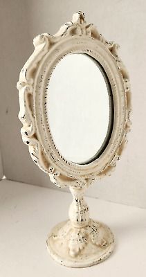 an old fashioned white vanity mirror sitting on top of a table next to a wall