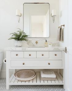 a white bathroom vanity with a mirror above it and a basket on the counter top