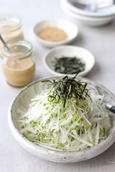 a white bowl filled with shredded greens and seasoning on top of a table next to other dishes