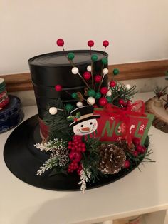 a decorated hat sitting on top of a counter next to christmas decorations and pine cones