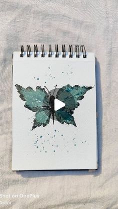 a drawing of a green butterfly on a white paper with black marker markers in front of it