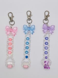 three key chains with bows and beads on them