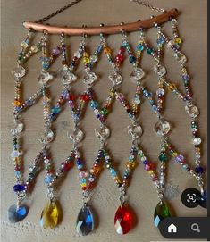 a multicolored beaded necklace hanging from a metal chain on a wooden surface