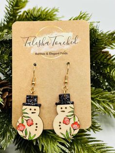 a pair of snowman earrings hanging from a christmas tree