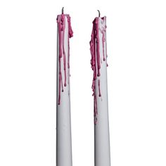 two white candles with pink sprinkles on them are standing in front of each other