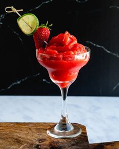 a red drink with strawberries and lime garnish