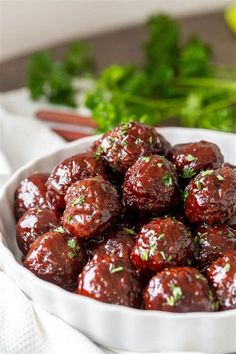 a white bowl filled with meatballs and garnished with parsley