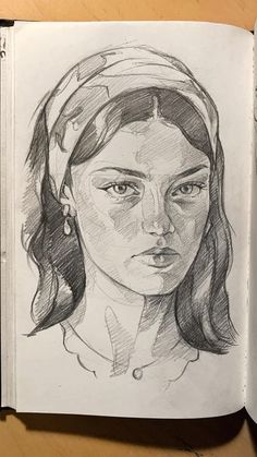 a drawing of a woman's face is shown in an open book on a table