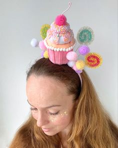 a woman with long hair wearing a pink cupcake headband on top of her head