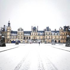 a large building that has snow on the ground and people walking in front of it