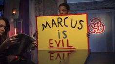 a woman holding a sign that reads marcs is evil eat and a man standing next to her