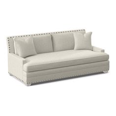 a white couch with four pillows on it's back and one arm facing the camera