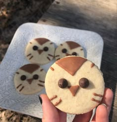 a person holding up a cookie shaped like a cat with eyes and nose on it