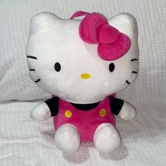 a hello kitty stuffed animal with a pink bow on its head sitting on a white sheet